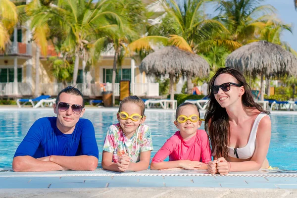 Família jovem com duas crianças desfrutar de férias de verão na piscina exterior — Fotografia de Stock
