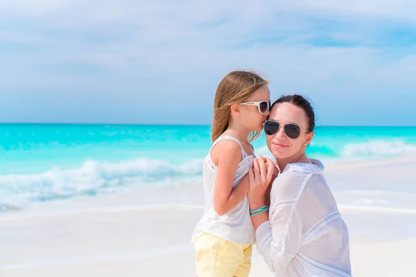 Klein schattig meisje en jonge moeder op tropisch strand — Stockfoto