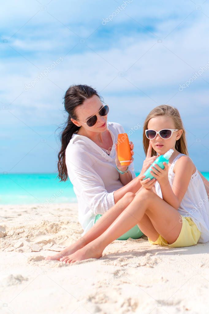 Mom applying sun cream to kid nose on the beach. The concept of protection from ultraviolet radiation