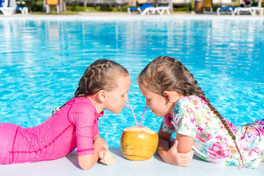 Kids in outdoor swimming pool drink coconut milk