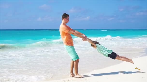 Kleine meisje en een jonge vader plezier tijdens tropische strandvakantie. Slow Motion — Stockvideo