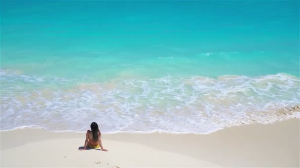 Молода жінка на пляжі з видом на воду над — стокове відео