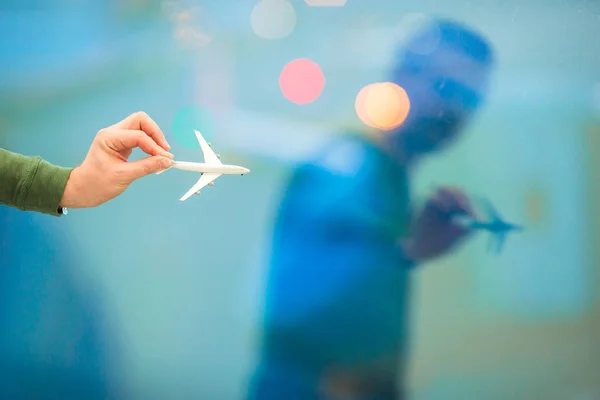Mão de close-up segurando um brinquedo modelo de avião no fundo do aeroporto grande janela — Fotografia de Stock