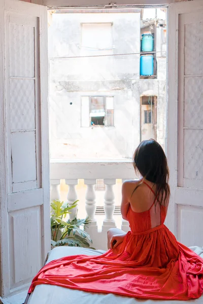 Joven atractiva mujer vestida de rojo en la cama del hotel en La Habana Vieja —  Fotos de Stock