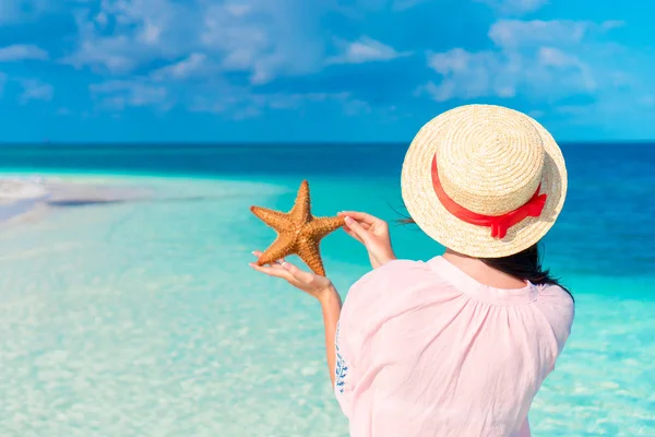 Rear view of young woman with starfish on white beach in the nature reserve — Stock Photo, Image