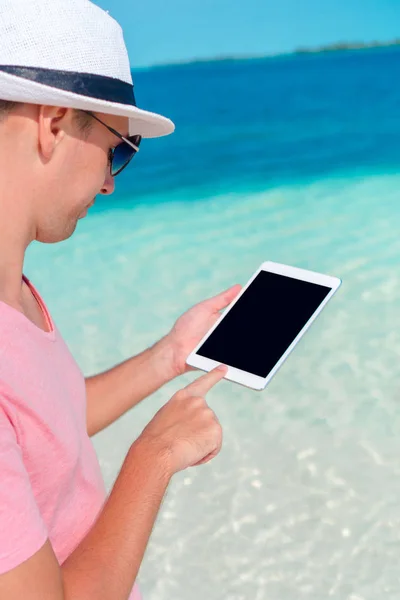Молодой человек с ноутбуком на фоне бирюзового океана на тропическом пляже — стоковое фото