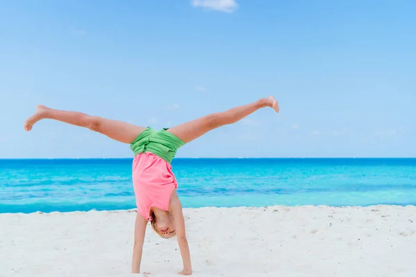 Actief meisje op het strand heeft veel plezier. Sportief kind maakt het wiel aan de kust — Stockfoto
