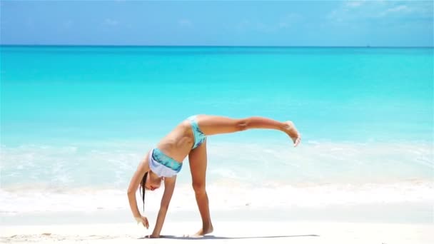 Adorable little girl at beach having a lot of fun. Sporty active kid making the wheel. SLOW MOTION — Stock Video