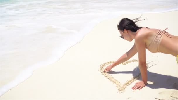 Giovane donna sulla spiaggia disegno sulla sabbia bianca — Video Stock
