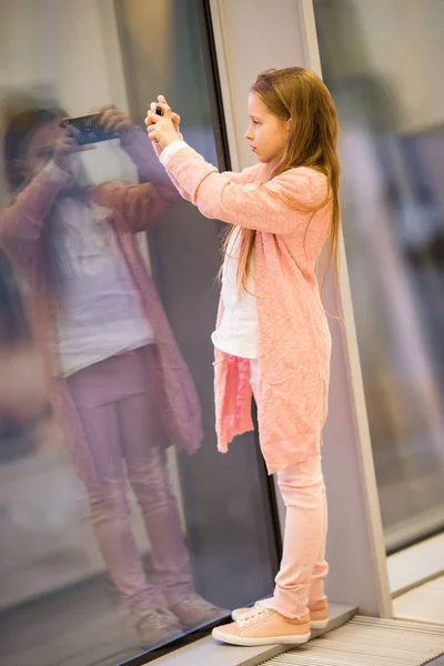 Malá holka na letišti v blízkosti velkého okna, zatímco čekat na nástup — Stock fotografie