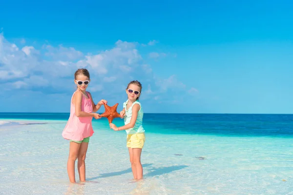 Adorable little girls holding giant red starfish — Stock Photo, Image