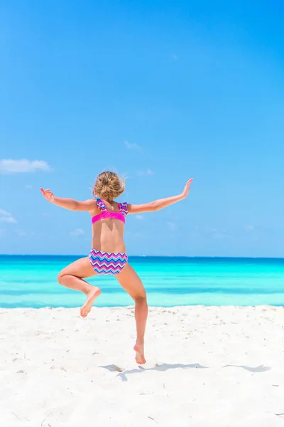 Sportovní malá holčička s hodně zábavy na bílé písečné pláži — Stock fotografie