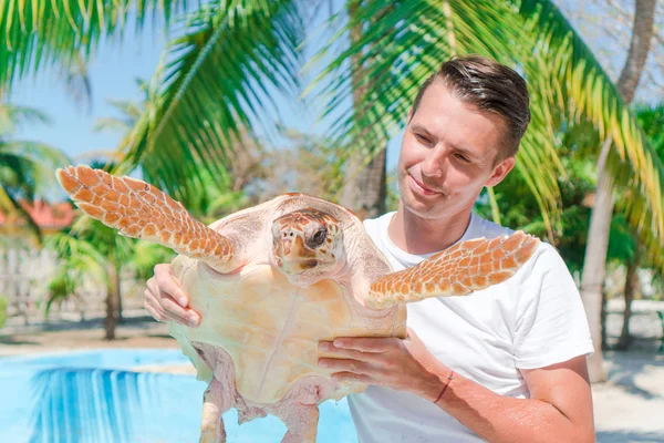 Toeristische man met zeeschildpad in de handen in de exotische reserve — Stockfoto