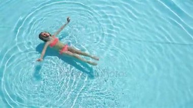 Sevimli mutlu küçük kız havuzda yüzmenin tadını çıkarıyor. Aile yaz tatili, çocuk bilardoda dinleniyor..