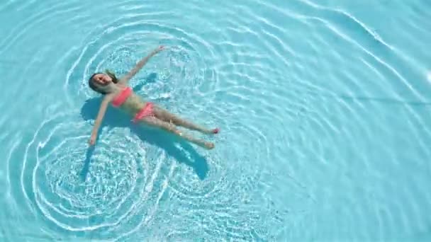 Entzückend glückliches kleines Mädchen genießt das Schwimmen im Pool. Sommerurlaub für die Familie, Kind entspannen am Pool. — Stockvideo