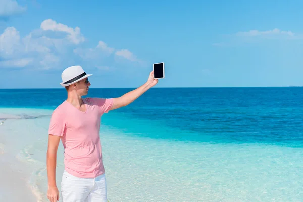 Jeune homme avec ordinateur portable sur la plage tropicale — Photo