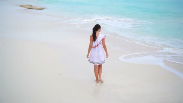 Mooie jongedame aan tropische kust. Achteraanzicht van een jong meisje in een mooie jurk achtergrond de zee — Stockvideo