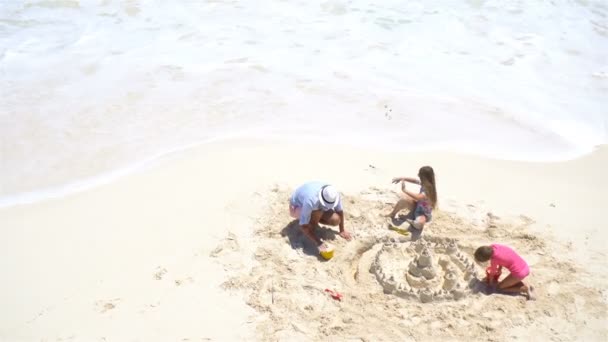 View from above to father and little daughters making sand castle at tropical beach — Stock Video