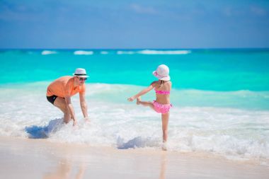 Küçük kız ve mutlu baba kumsal tatili boyunca eğleniyorlar.