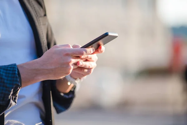 De close-up van mannelijke handen houdt zijn mobieltje buiten op straat. Man met mobiele smartphone. — Stockfoto