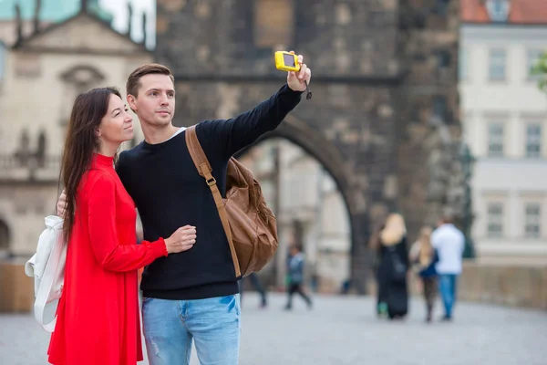 Casal jovem viajando em férias na Europa sorrindo feliz. Família caucasiana fazendo selfie no popular Karlov Most — Fotografia de Stock