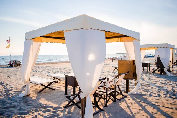 Tumbonas de madera frente a un mar turquesa a la luz de la tarde. Tumbonas en la famosa playa de arena italiana en Forte dei Marmi —  Fotos de Stock