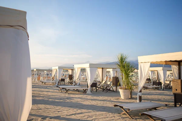 Trä solstolar i mjukt kvällsljus. Solstolar i berömda italienska sandstrand på Forte dei Marmi — Stockfoto