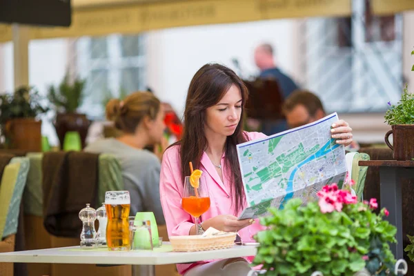 Piękna kobieta, siedząc w kawiarni odkryty z mapą. Szczęśliwy turysta cieszyć wakacje Europejskiej restauracji openair — Zdjęcie stockowe