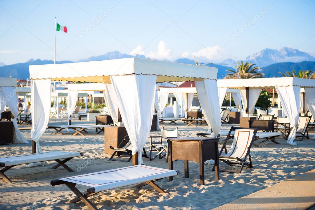 Wooden sunbeds in front of a turquoise sea in the evening light. Sunbeds in famous italian sand beach at Forte dei Marmi