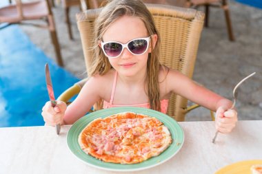 Tatlı küçük kız öğle yemeğinde pizza yiyor.