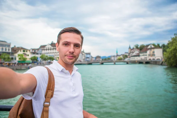 Ung man tar selfie bakgrund berömda Fraumunster kyrkan och floden Limmat, Schweiz. — Stockfoto