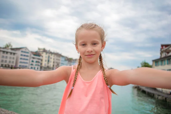 Adorable niñita tomando selfie al aire libre en Zurich, Suiza. Primer plano retrato de niño fondo de hermosa ciudad —  Fotos de Stock