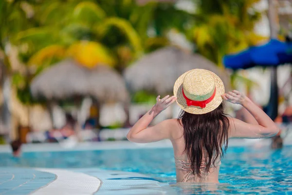 Mooie jonge vrouw ontspannen in het zwembad. Achteraanzicht van meisje in buitenzwembad in luxehotel — Stockfoto