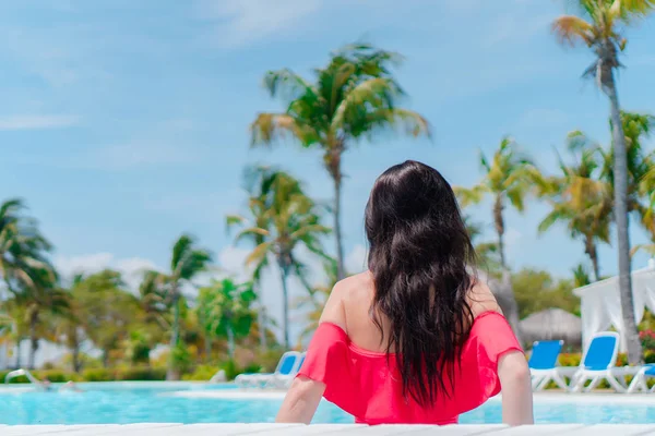 Schöne junge Frau entspannt sich im Schwimmbad. Glückliches Mädchen im Außenpool eines Luxushotels — Stockfoto