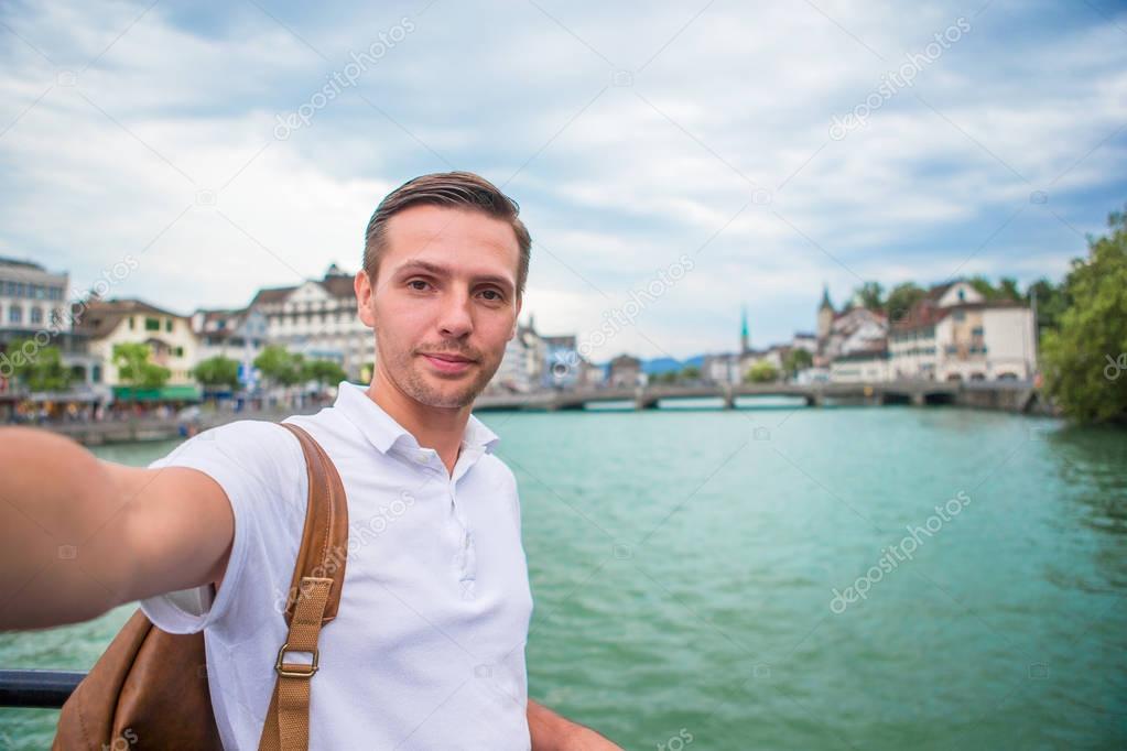 Young man taking selfie background famous Fraumunster Church and river Limmat, Switzerland.