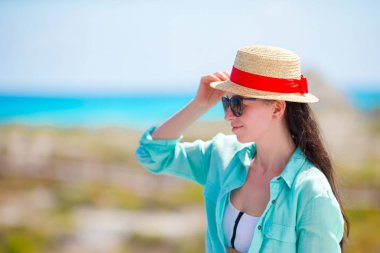 Tropikal bir plajda şapkalı genç kadın