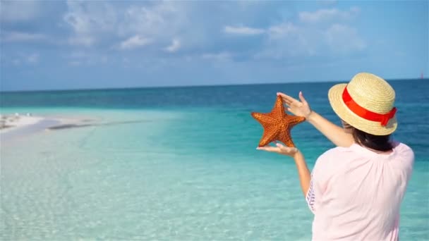 Young woman with starfish on white beach in the nature reserve — Stock Video