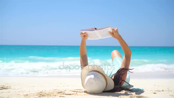 Mujer joven está leyendo en la playa tropical blanca — Vídeos de Stock