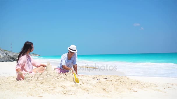 Familie van vier maken zandkasteel op tropisch strand — Stockvideo