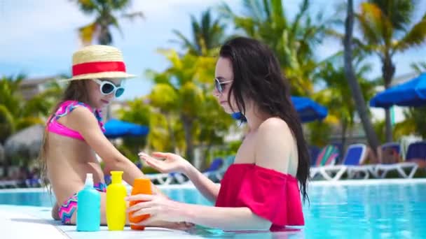 Jonge moeder brengt zonnecrème aan op de neus van een kind in het zwembad. Het begrip bescherming tegen ultraviolette straling — Stockvideo