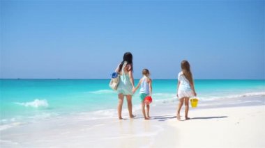 Sevimli küçük kızlar ve beyaz sahilde genç bir anne.