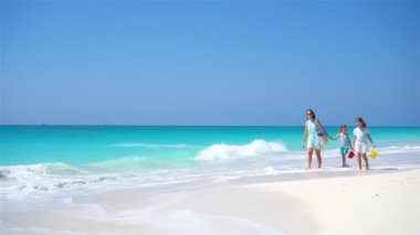 Anne ve çocukların ailesi beyaz sahilde yürüyor.