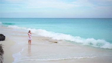 Kumsalda genç ve güzel bir kadın sığ sularda yürüyor..