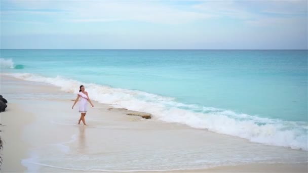 Gyönyörű fiatal nő a tengerparton, aki sekély vízben sétál. — Stock videók