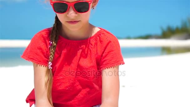 Портрет очаровательной маленькой девочки на пляже во время летних каникул. Счастливый ребенок играет с песком. Медленное движение — стоковое видео
