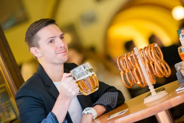 Junger Mann mit Bier und Salzbrezeln in Biersportbar — Stockfoto