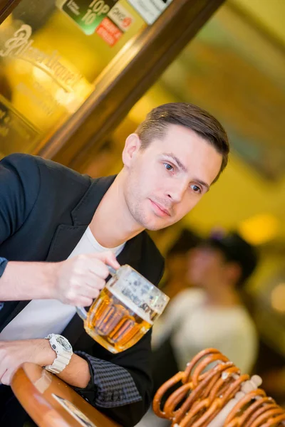 Jonge man met bier en gezouten zachte krakelingen in sport Biercafé — Stockfoto