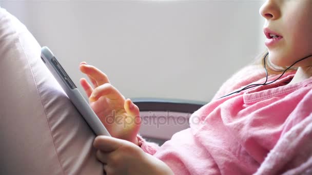 Очаровательная маленькая девочка путешествует на самолёте. Симпатичный ребенок с ноутбуком возле окна в самолете — стоковое видео