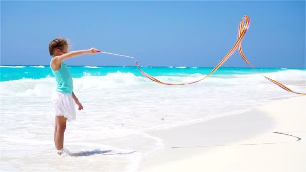 Sevimli küçük kız jimnastik kurdele ile sahilde oynarken. Ağır çekim — Stok video