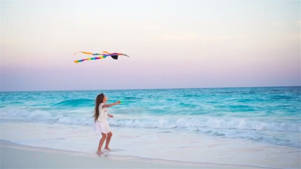 Niña con cometa voladora en la playa tropical. Juego de niños en la orilla del océano. Niño con juguetes de playa en cámara lenta — Vídeo de stock